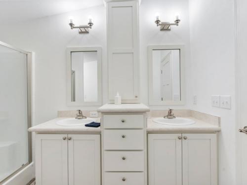 A bathroom with white cabinets and sinks.